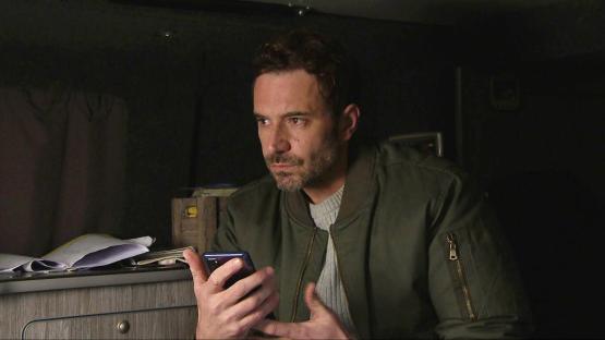 Oliver Farnworth, portraying John Sugden in Emmerdale, listens anxiously to a voicemail.