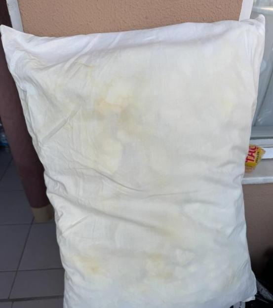 A dirty pillow with yellow and brown stains.