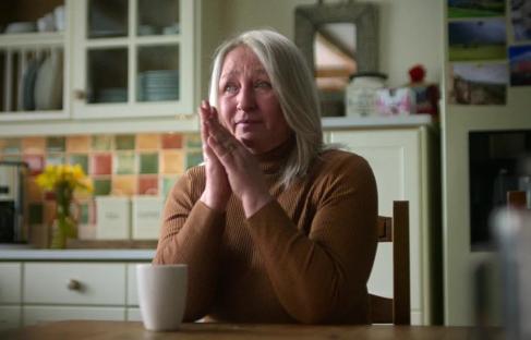 Mary-Ann Mitchell, half-sister of Fred and Rose West's victim Juanita, sits at a kitchen table, hands clasped.