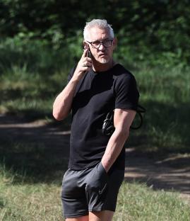 Gary Lineker on a phone call in a park.