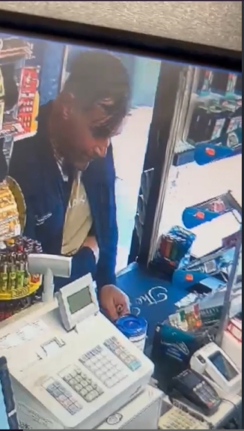 Surveillance image of a theft: a man stealing a charity box from a shop counter.