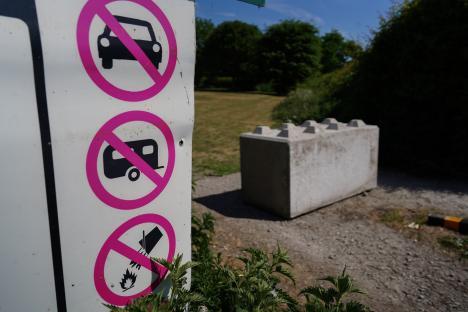 No parking, camping, or fires sign with concrete barrier in background.