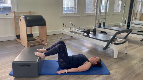 Woman doing Pilates leg exercise on reformer.