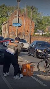 Two men hugging on a street near a Just Eat delivery bag.