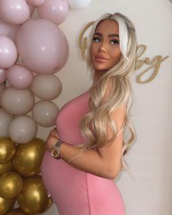 Pregnant woman in pink dress in front of balloons and 