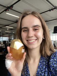 Woman holding a gold and amber perfume bottle.