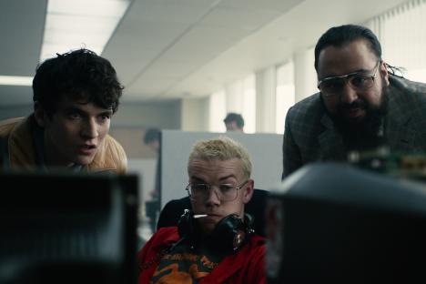 Scene from Black Mirror: Bandersnatch showing three men looking intently at a computer screen.