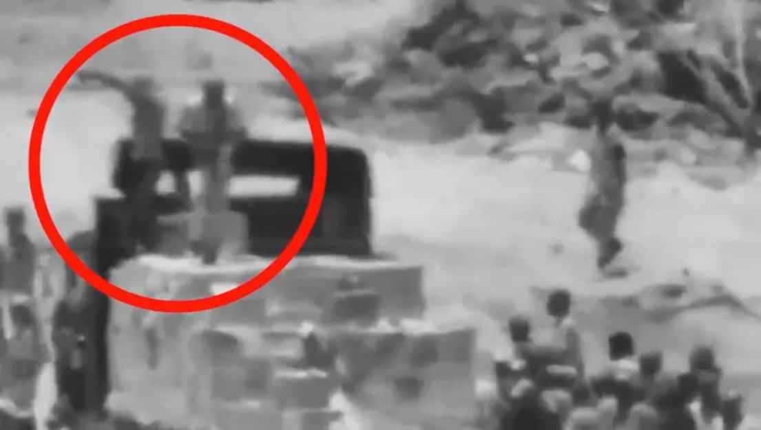 Security camera footage showing a person holding a gun while another person points.