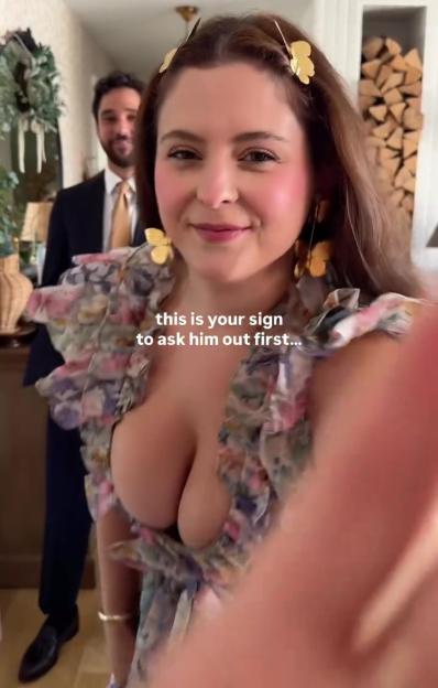 Woman in low-cut dress with a man in the background; text overlay reads "this is your sign to ask him out first..."