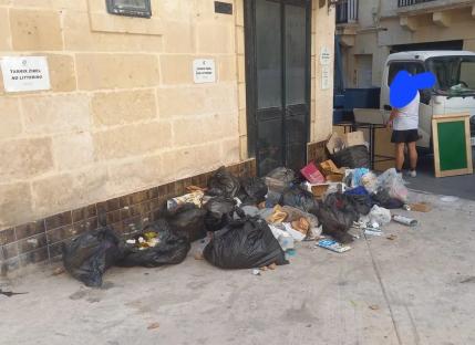 Pile of garbage bags on the sidewalk next to a building.