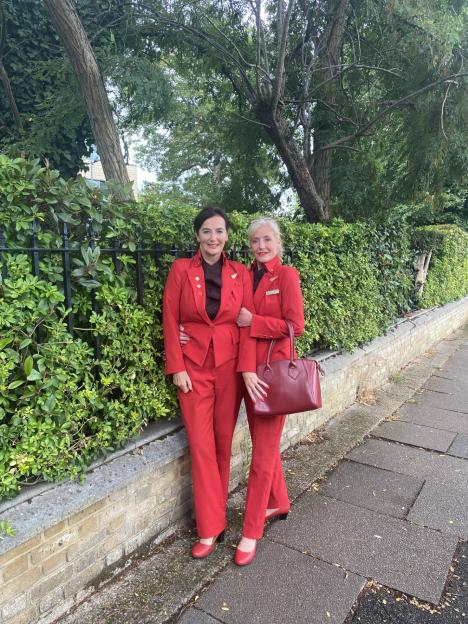 Two women in red suits stand outside.