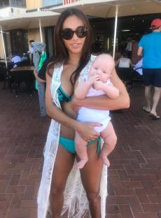 Woman in a swimsuit holding a baby.