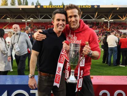 Rob McElhenney and Ryan Reynolds holding the EFL Trophy.