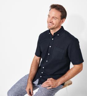 Man wearing a dark navy short-sleeved shirt and light gray linen pants.
