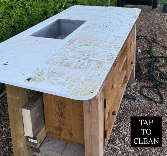 A dirty, white countertop on a wooden kitchen island.
