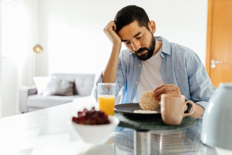 Depressed man with a small appetite eating breakfast.
