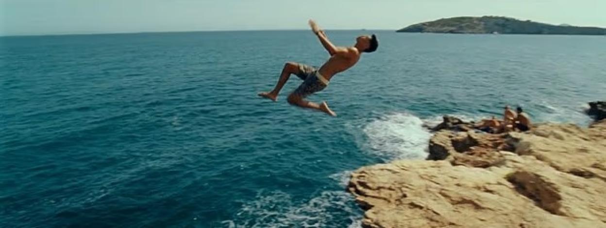 Man backflipping into ocean from cliff.