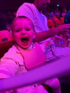 Toddler with open mouth in a pink bib at a show.