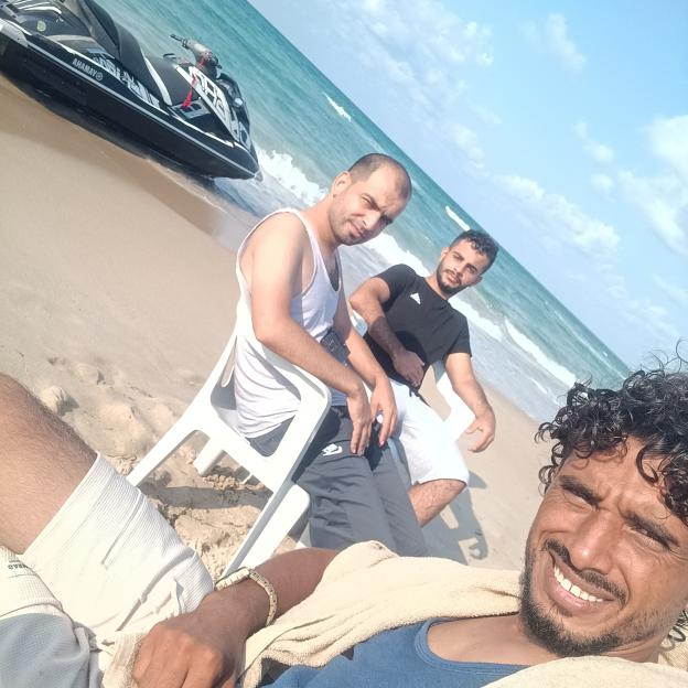 Selfie of Muhammad Abu Dakha with two other Palestinian migrants on a beach with a jet ski nearby, before sailing to Lampedusa, Italy, to seek asylum.