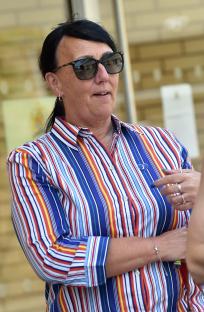 A woman wearing sunglasses and a striped shirt outside a coroner's court.
