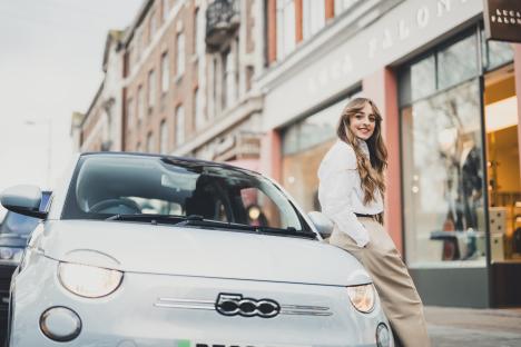 Woman leaning against a Fiat 500.