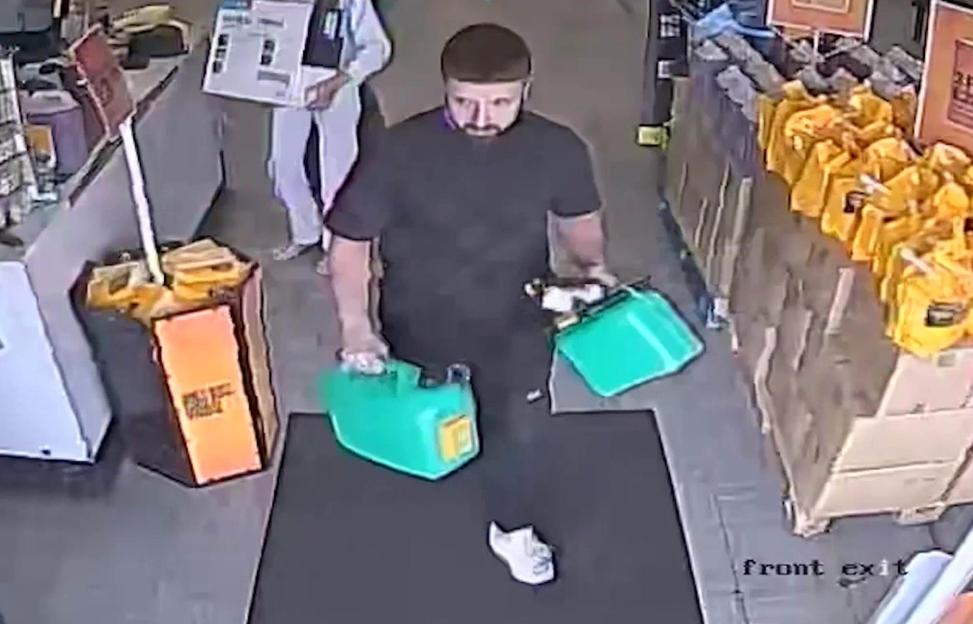 CCTV image of a man carrying two petrol cans.