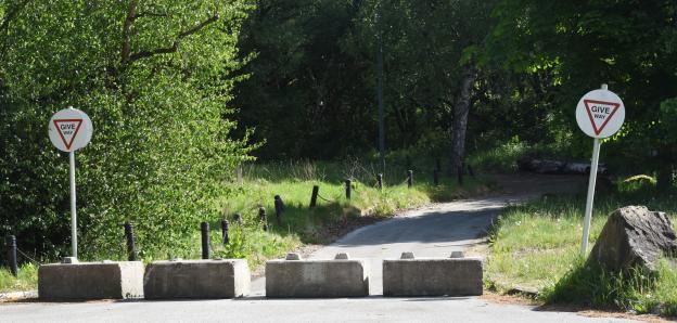 Give way signs and concrete barriers blocking a roadway.
