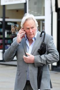 A man in a gray suit talks on his cell phone.