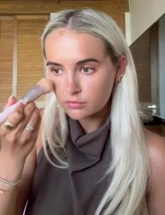 Woman applying makeup with a brush.