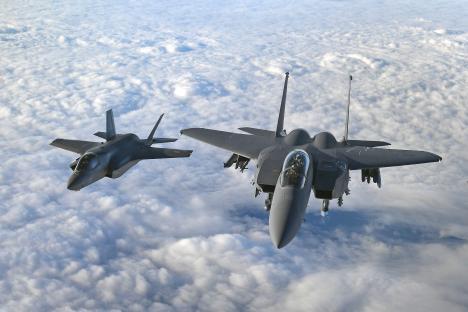 RAF F-35B Lightning and US Air Force F-15 Strike Eagle fighter jets flying above clouds.