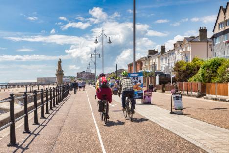 people riding bikes on a sidewalk next to a sign that says fish & chips