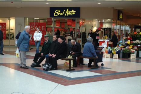 People sitting and standing in a shopping center.