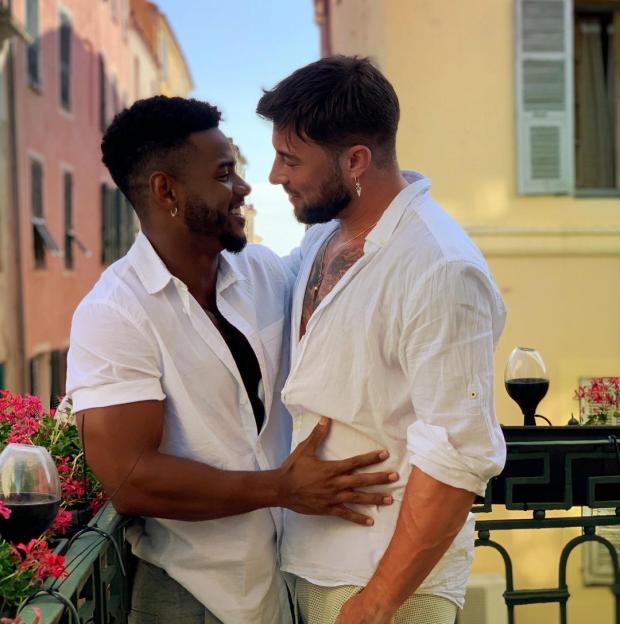 Two men embracing on a balcony.