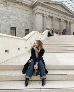 Woman sitting on steps outside a museum.