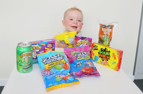 Toddler with various American sweets and drinks.