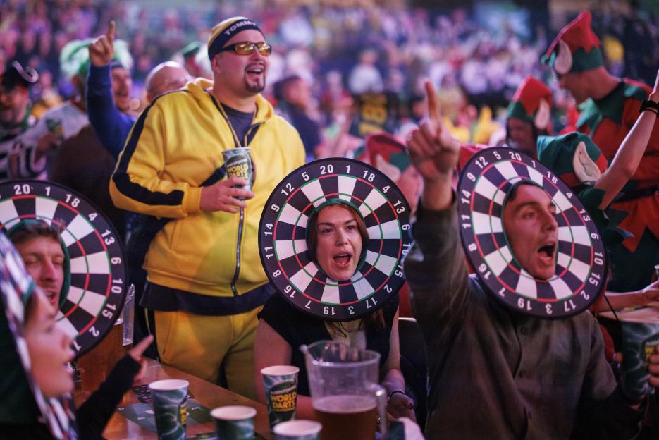 Fans attend the opening session of the World Darts Championship, with some wearing costumes like dartboards around their faces and others dressed as elves.