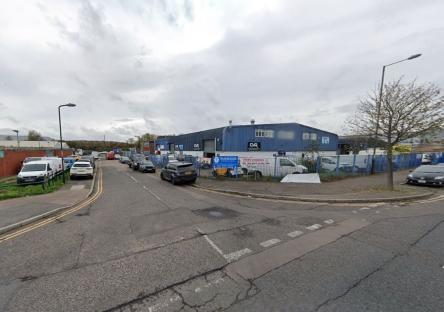 Street view of a blue industrial building with parked cars.