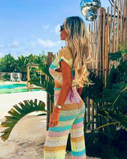 Woman in striped knit pants and top by the pool.