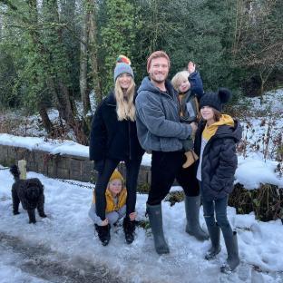 Family of five posing in the snow.