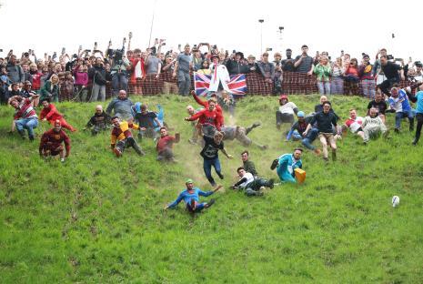 Contestants chase a cheese wheel down a hill during a cheese-rolling competition.