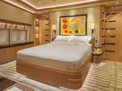 Private jet bedroom with large bed and artwork.