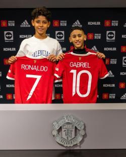 Two boys holding Manchester United jerseys with Ronaldo 7 and Gabriel 10 on the back.
