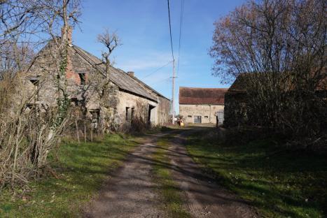 A dirt road leads between two stone buildings in a French village.