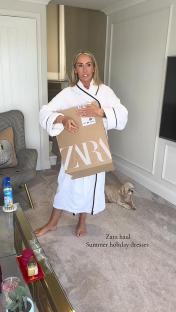 Woman in bathrobe holding Zara box of summer dresses.