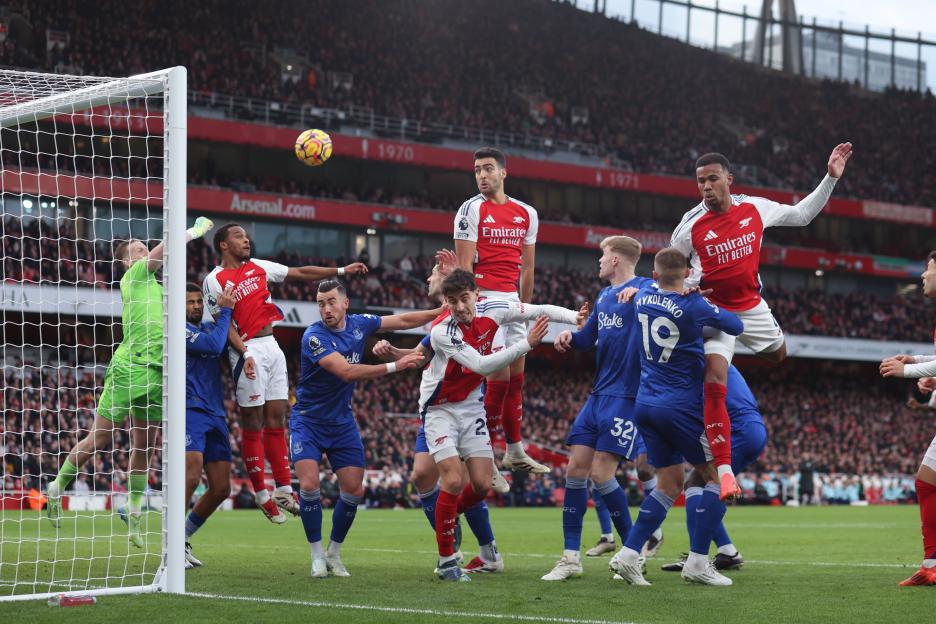 Arsenal and Everton players vying for the ball during a corner kick.