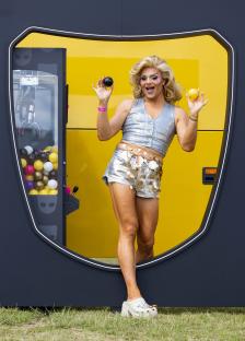Drag queen holding yellow and black balls in front of a yellow and black display.