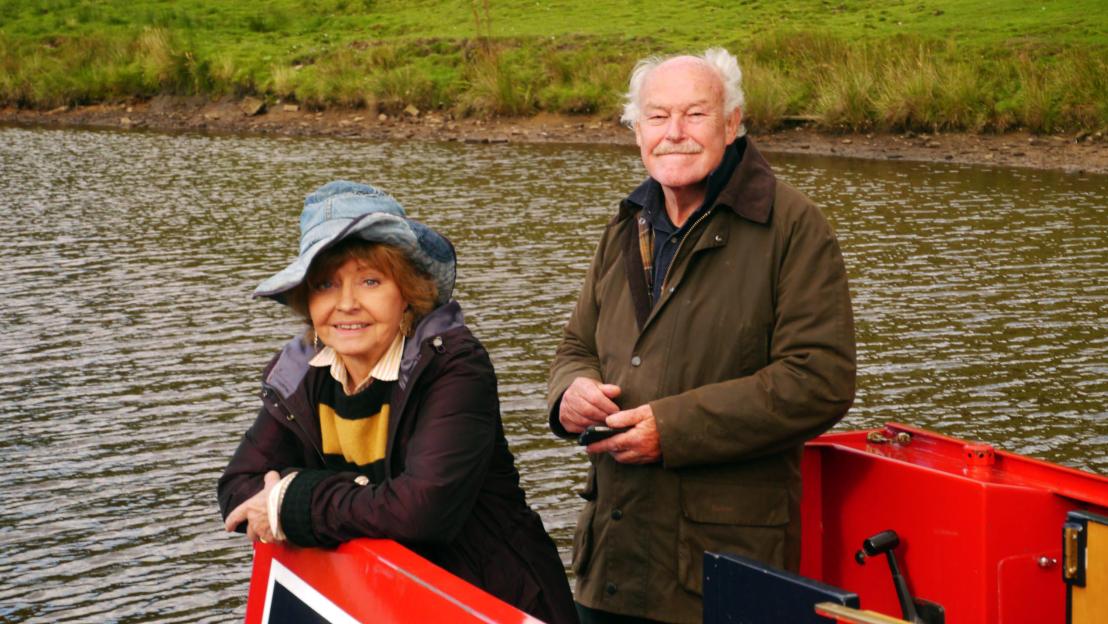 A man and a woman standing beside a body of water
