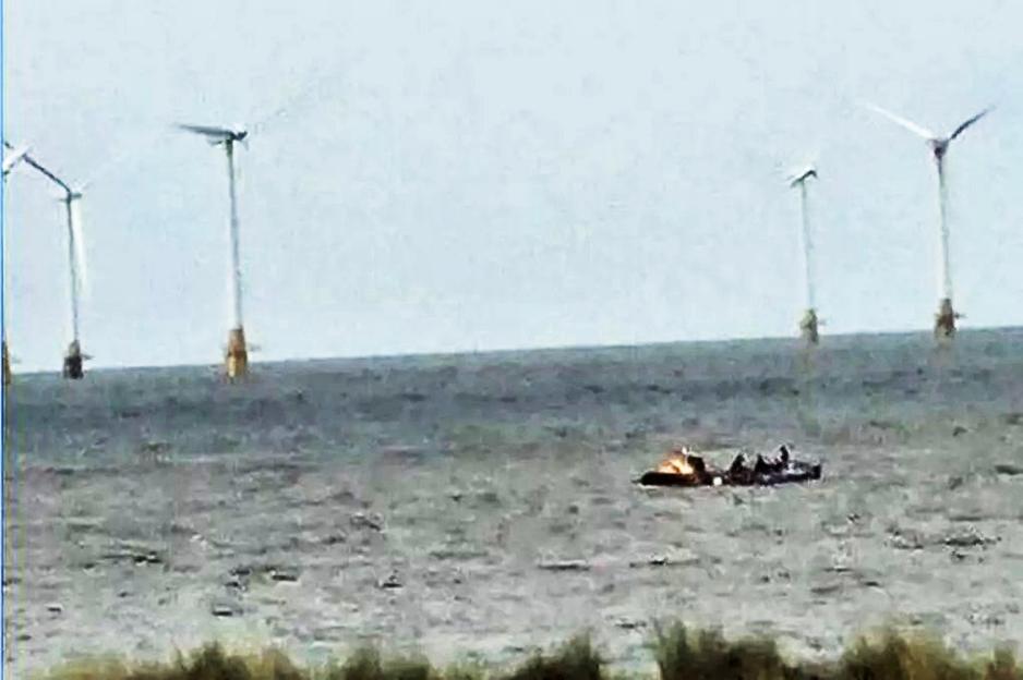 Photo of a small boat on the water near offshore wind turbines.