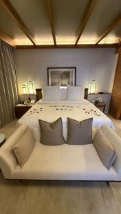 Hotel room with a bed and couch, welcome back message on the bed.