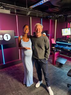 Pregnant Vick Hope and a man smiling in a radio studio.